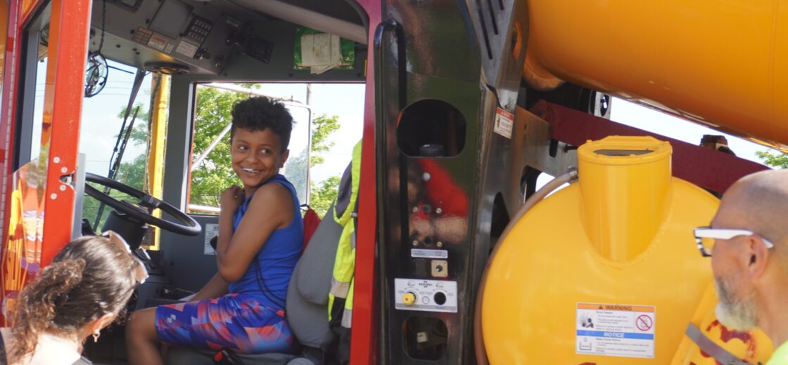 A picture of a truck and attendee at a community touch-a-truck event.