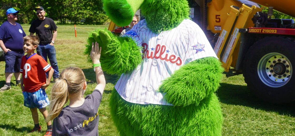 A photo of the Phillie Phanatic interacting with an attendee at the Silvi Foundation Touch-a-Truck.